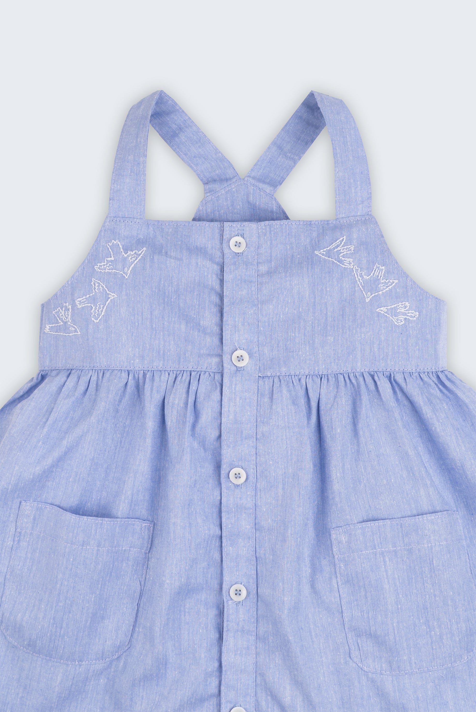 Vestido azul em linho e algodão infantil com pássaros bordados à mão para meninas, visto em detalhe.