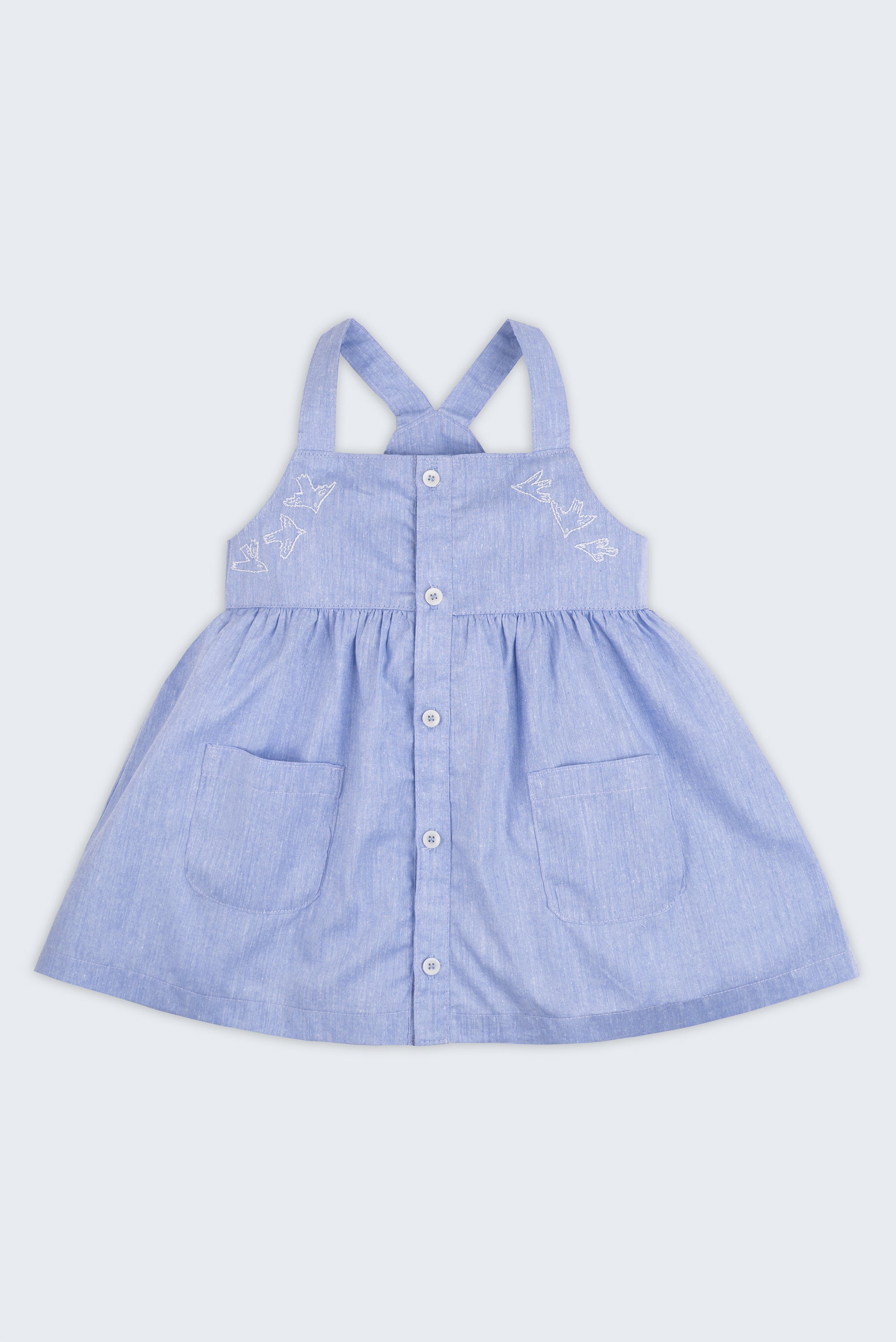 Vista completa de vestido infantil para meninas em linho e algodão azul com botões frontais, bordados de pássaros e bolsos.