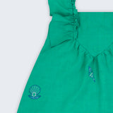 Vestido infantil em linho verde-água com bordado à mão de conchas e estrelas, visto de frente em detalhe.