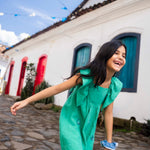 Menina usando vestido infantil em linho verde-água com bordado à mão de conchas do mar e mangas com babados.