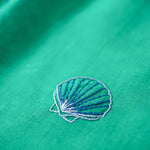 Detalhe do bordado à mão em concha do mar no vestido infantil em linho verde-água.