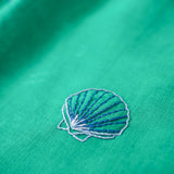 Detalhe do bordado à mão em concha do mar no vestido infantil em linho verde-água.