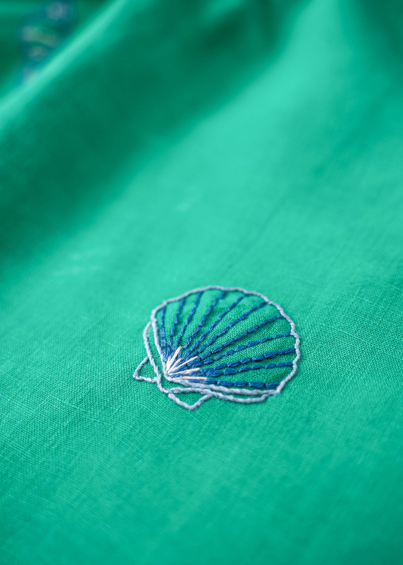 Detalhe do bordado à mão em concha do mar no vestido infantil em linho verde-água.