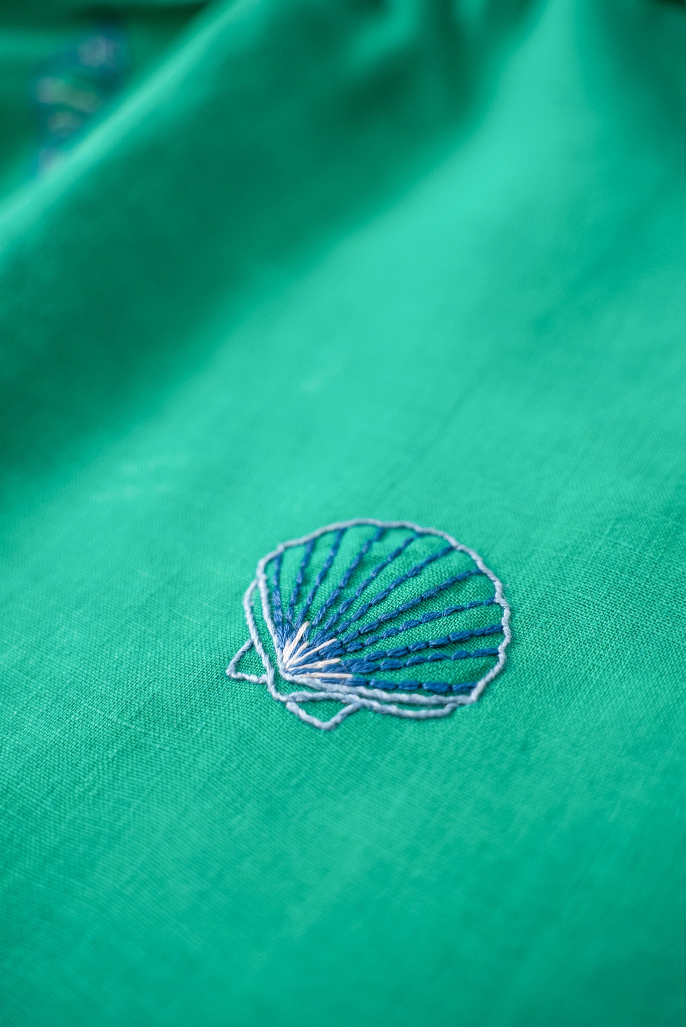 Detalhe do bordado à mão em concha do mar no vestido infantil em linho verde-água.