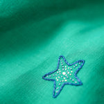 Detalhe do bordado à mão de estrela-do-mar no vestido infantil em linho verde-água.