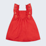 Vestido infantil de menina em linho vermelho com bordado artesanal de estrelas natalinas e babados delicados, visto de frente.