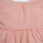 Vestido Pietra em puro linho rosa claro, com mangas e saia com babado, visto de costas em detalhe.