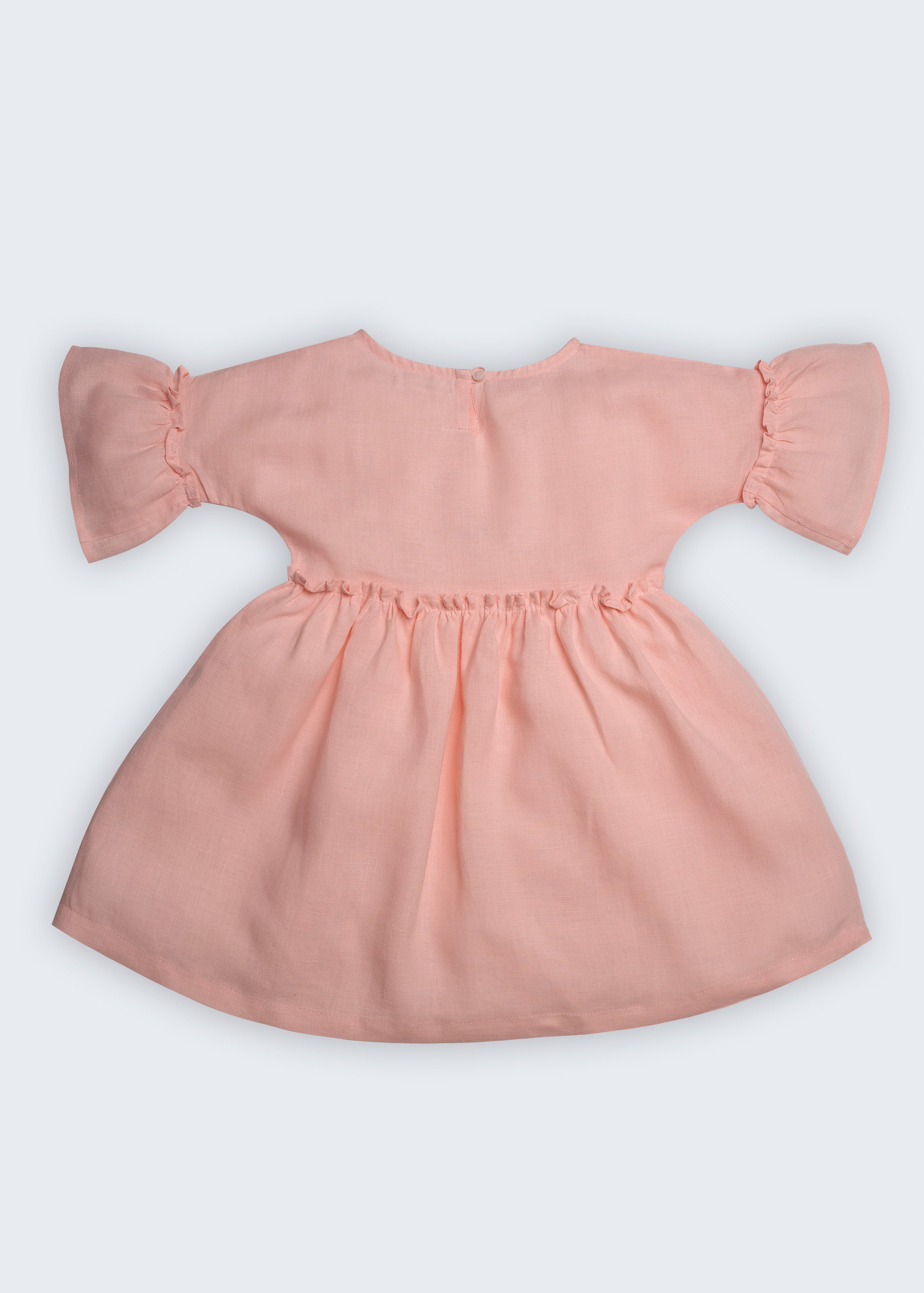 Vestido Pietra em puro linho rosa claro, com mangas e saia com babado, visto de costas.