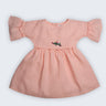 Vestido Pietra em puro linho rosa claro, com mangas e saia com babado e bordado manual de porquinhos, visto de frente.