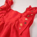 Close do bordado manual de estrelas nas alças de vestido infantil vermelho em linho.