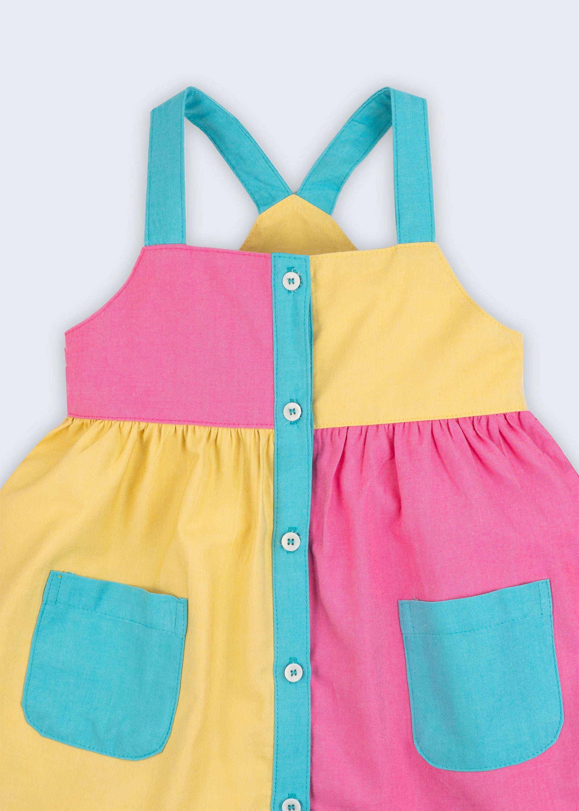 Detalhe do vestido infantil em viscose Ecovero™ e algodão BCI, mostrando alças azuis e contraste de cores.