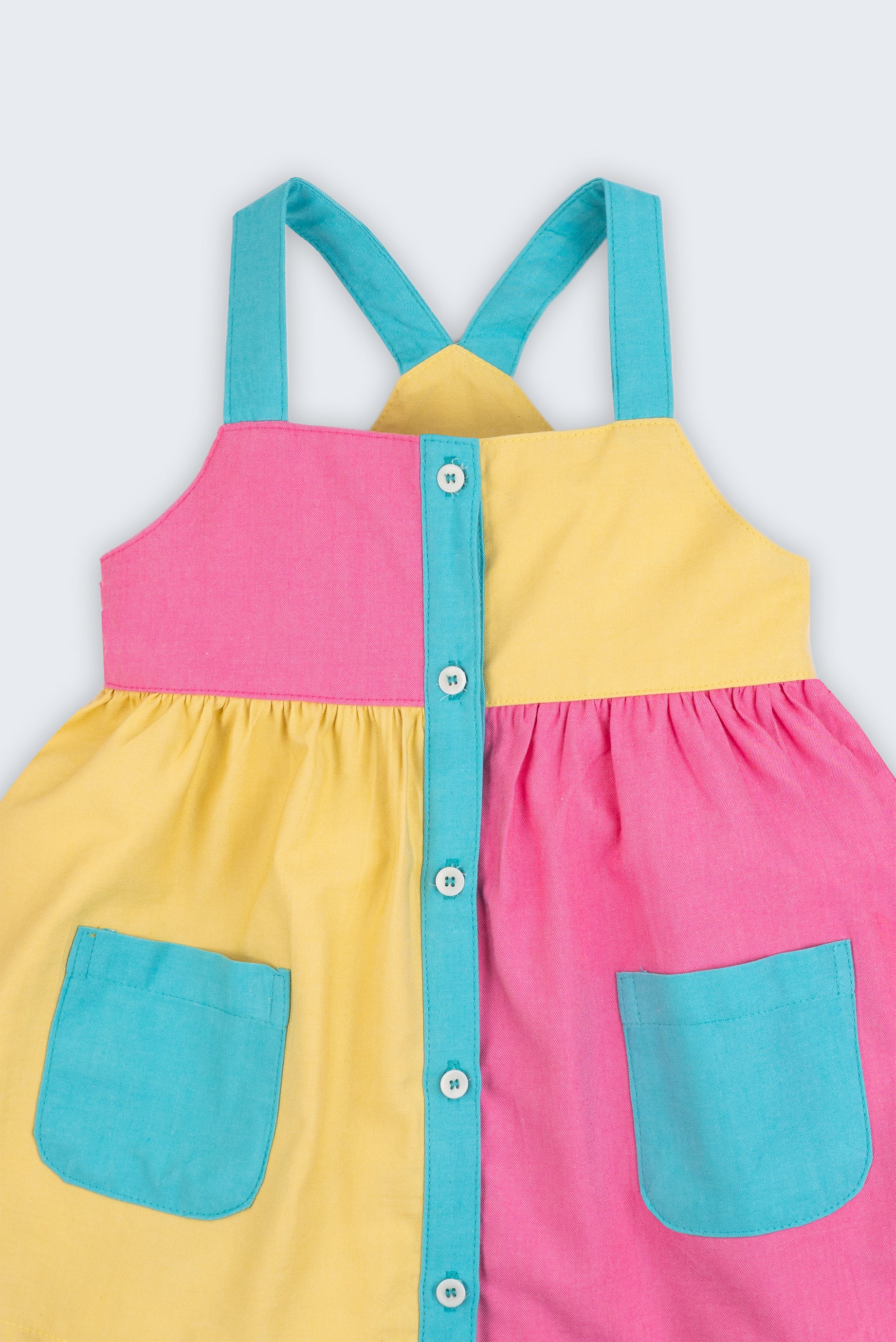 Detalhe do vestido infantil em viscose Ecovero™ e algodão BCI, mostrando alças azuis e contraste de cores.