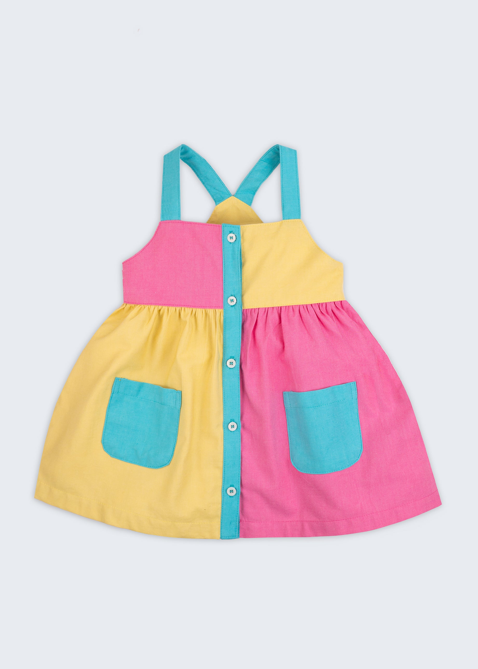 Vestido infantil color block em amarelo, rosa pink e azul turquesa para meninas, com bolsos frontais e alças retas, visto de frente.