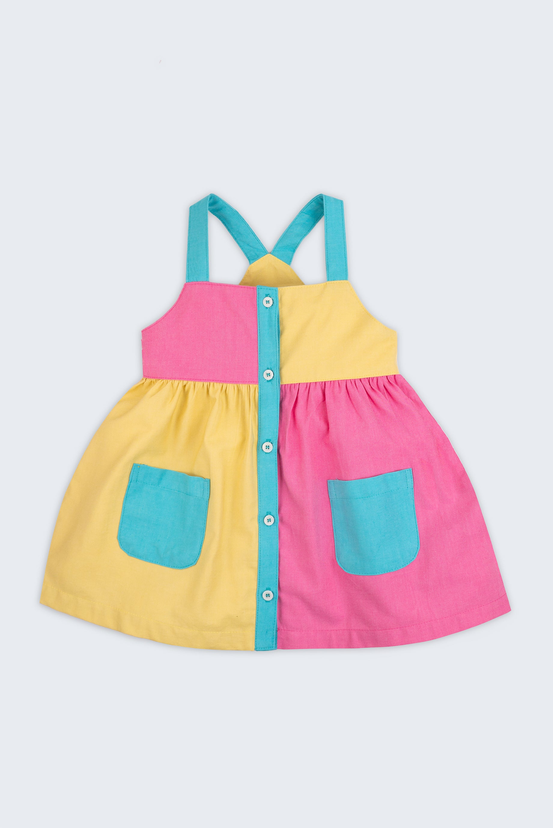 Vestido infantil color block em amarelo, rosa pink e azul turquesa para meninas, com bolsos frontais e alças retas, visto de frente.